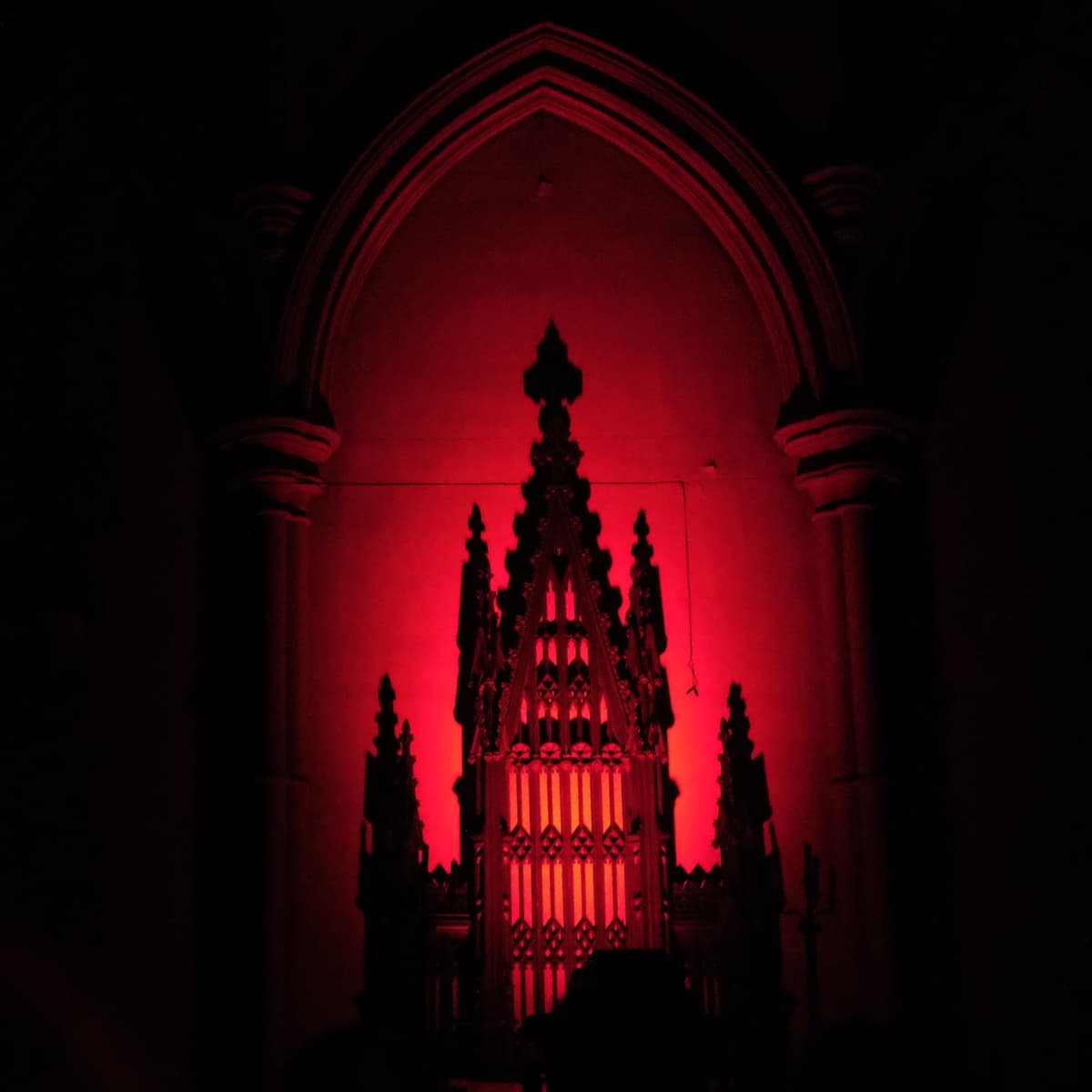 Gothic church tabernacle in the darkness, illuminated by a strong, ominous red light.